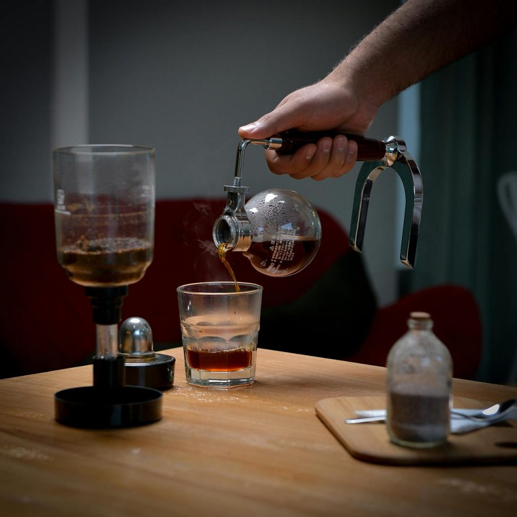 café vs thé : photographie d'une main versant du café dans un verre transparent